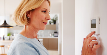 Woman with blonde hair pushing buttons on a thermostat